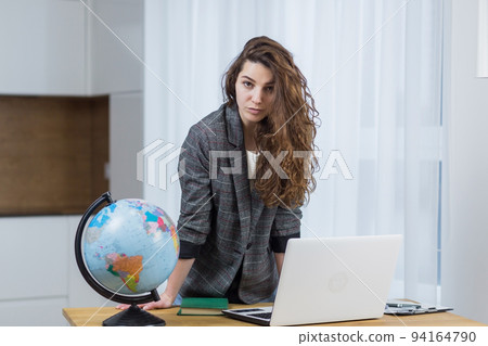 Young female teacher, travel agency worker teaches online from laptop, shows globe, tells via video call Young female teacher, travel agency worker teaches online from laptop, shows globe, tells via video call 94164790