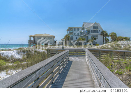 View of beach houses from a wooden boardwalk on a beach at Destin, Florida 94165591
