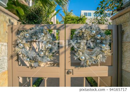 La Jolla, California- Two silver wreaths on a painted beige double gate 94165717