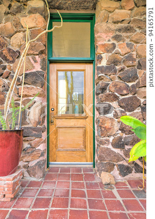 Wooden front door with glass panel and transom window in between a rockwall at Tucson, AZ Wooden front door with glass panel and transom window in between a rockwall at Tucson, AZ 94165791