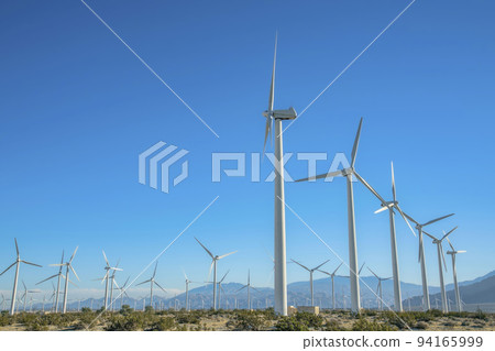 Sunny day view of windmills with mountains and clear blue sky background Sunny day view of windmills with mountains and clear blue sky background 94165999