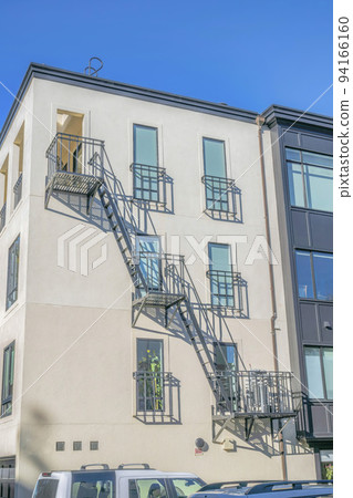 Residential building with fire exit stairway against blue sky on a sunny day Residential building with fire exit stairway against blue sky on a sunny day 94166160