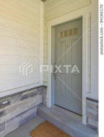 Vertical Gray front door of a townhome with glass panes and doormat 94166178
