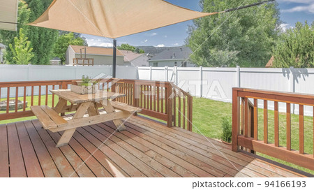 Panorama Whispy white clouds Wooden deck with a sunshade over the table with bench seats 94166193