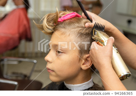 Nice european boy getting hairstyle in barbershop. 94166365
