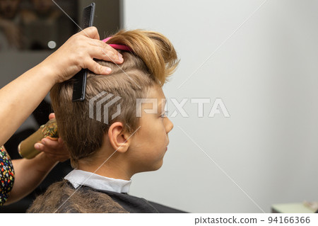 Nice european boy getting hairstyle in barbershop. 94166366