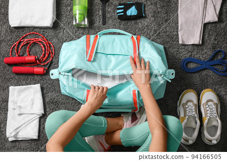 Woman with bag and sports items on grey carpet, top view Woman with bag and sports items on grey carpet, top view 94166505