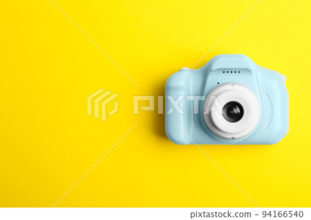 Light blue toy camera on yellow background, top view with space for text. Future photographer 94166540