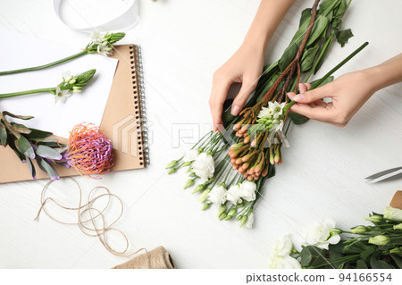 Florist making beautiful bouquet at white wooden table, top view 94166554