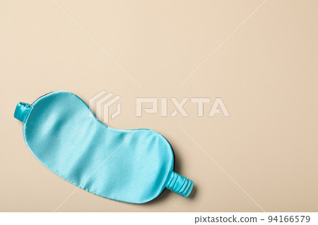Turquoise sleeping mask on yellow background, top view with space for text. Bedtime accessory 94166579