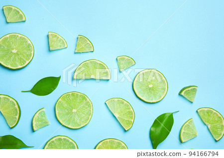 Juicy fresh lime slices and green leaves on light blue background, flat lay. Space for text Juicy fresh lime slices and green leaves on light blue background, flat lay. Space for text 94166794