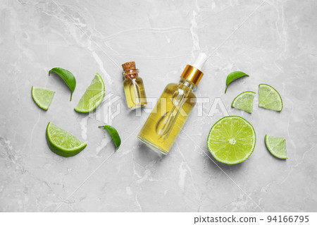 Flat lay composition with lime essential oil on light grey marble background 94166795