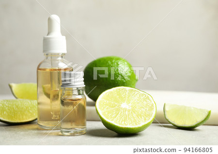 Lime essential oil and cut citrus fruits on light table Lime essential oil and cut citrus fruits on light table 94166805