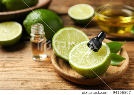 Dropper with lime essential oil and cut citrus fruit on wooden table Dropper with lime essential oil and cut citrus fruit on wooden table 94166807