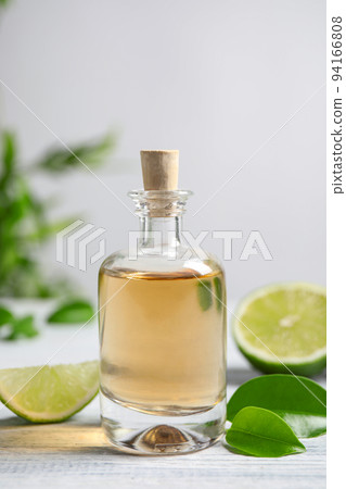 Lime essential oil and cut citrus fruits on white wooden table Lime essential oil and cut citrus fruits on white wooden table 94166808