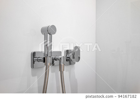 Chromium bidet shower with white tiles in a toilet. Clean and new spray shower. Chromium bidet shower with white tiles in a toilet. Clean and new spray shower. 94167182