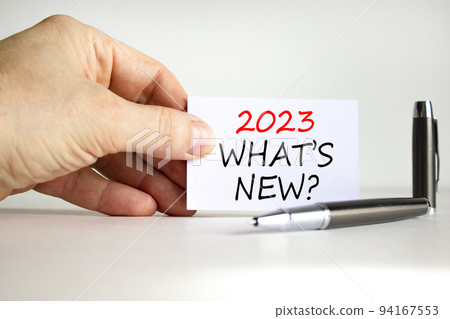 2023 what is new symbol. White card with words 2023 what is new. Businessman hand. Metallic pen. Beautiful white table white background. Business and 2023 what is new concept. Copy space. 94167553