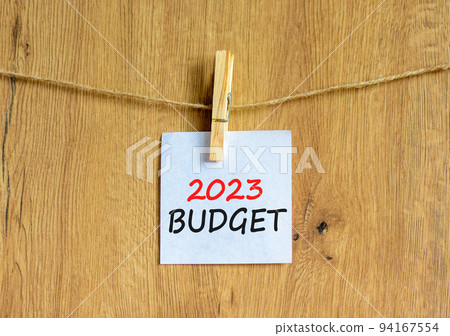 2023 Budget symbol. White paper with words 2023 Budget, clip on wooden clothespin. Beautiful wooden background. Business and 2023 budget concept. Copy space. 2023 Budget symbol. White paper with words 2023 Budget, clip on wooden clothespin. Beautiful wooden background. Business and 2023 budget concept. Copy space. 94167554