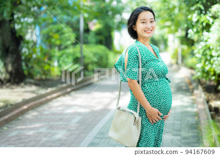 Pregnant woman walking on green road Pregnant woman walking on green road 94167609