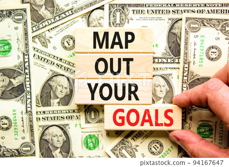 Support and map out your goals symbol. Concept words Map out your goals on wooden blocks on beautiful background from dollar bills. Businessman hand. Business, support and map out your goals concept Support and map out your goals symbol. Concept words Map out your goals on wooden blocks on beautiful background from dollar bills. Businessman hand. Business, support and map out your goals concept 94167647