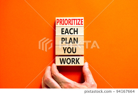 Prioritize each plan you work symbol. Concept words Prioritize each plan you work on blocks on beautiful orange background. Businessman hand. Business prioritize each plan you work concept. Copy space 94167664
