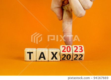 2023 tax new year symbol. Businessman turns a wooden cube and changes words Tax 2022 to Tax 2023. Beautiful orange table orange background, copy space. Business 2023 tax new year concept. 2023 tax new year symbol. Businessman turns a wooden cube and changes words Tax 2022 to Tax 2023. Beautiful orange table orange background, copy space. Business 2023 tax new year concept. 94167669