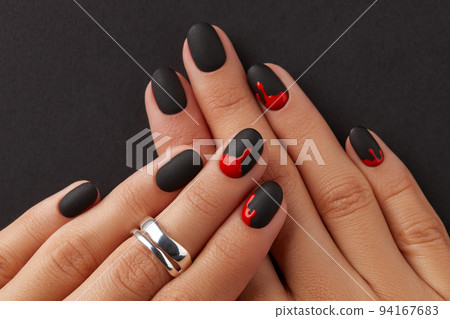 Manicured female hands with fashion accessories on black. Trendy autumn halloween bloody spooky nail design. Manicured female hands with fashion accessories on black. Trendy autumn halloween bloody spooky nail design. 94167683