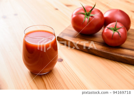 Tomato juice in a glass and tomatoes on a wooden cutting board 94169718
