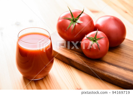 Tomato juice in a glass and tomatoes on a wooden cutting board 94169719