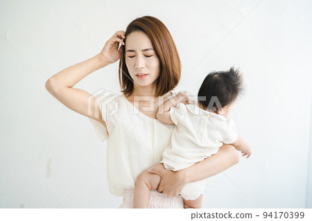 A mother holding a baby and looking tired 94170399
