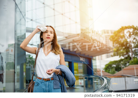 Asian beautiful business woman drying sweat her face with cloth in warm summer day hot weather Asian beautiful business woman drying sweat her face with cloth in warm summer day hot weather 94171319