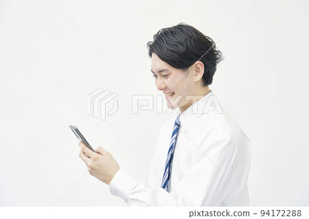 A businessman looking at a smartphone on a white background A businessman looking at a smartphone on a white background 94172288
