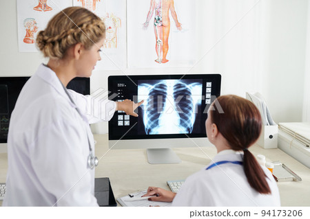 Pulmonologust and surgeon discussing chest x-ray of sick patient on computer screen Pulmonologust and surgeon discussing chest x-ray of sick patient on computer screen 94173206