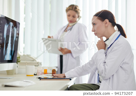 Pensive medical researcher looking at computer screen with lung x-ray of patient recovered after coronavirus 94173207