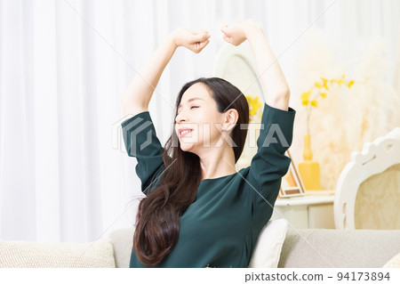 Woman taking a deep breath on the sofa in the living room 94173894