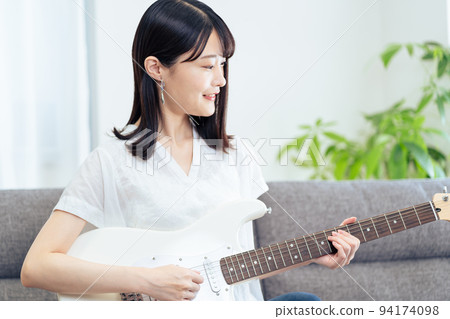 坐在沙發上彈吉他的女人 坐在沙發上彈吉他的女人 94174098