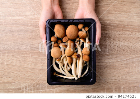 Fresh yanagi matsutake mushroom in package holding by hand on wooden background 94174523