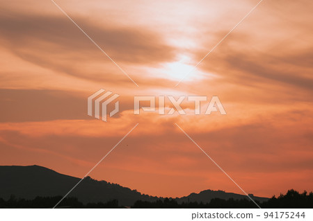 Red sunset, sun behind clouds and mountains 94175244
