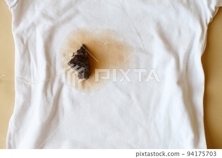 spilled tea stain on white clothes with a tea bag next to it spilled tea stain on white clothes with a tea bag next to it 94175703