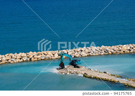 The excavator moves stones into the sea. Construction of breakwaters to protect the beach in Netanya in Israel. The excavator moves stones into the sea. Construction of breakwaters to protect the beach in Netanya in Israel. 94175765