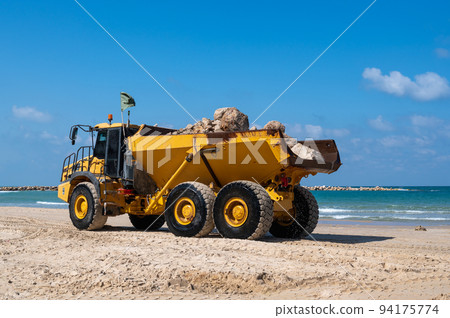 A large mining truck transports stones to build breakwaters to protect a beach in Netanya, Israel. 94175774