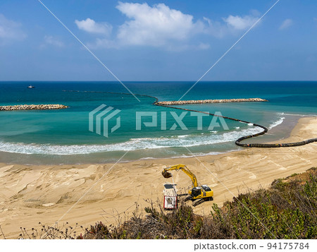 The excavator transports a change house for workers. Building a beach in Netanya in Israel. The excavator transports a change house for workers. Building a beach in Netanya in Israel. 94175784