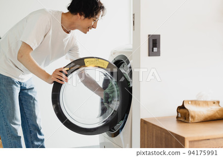 一名男子將衣物放入滾筒洗衣機中 94175991