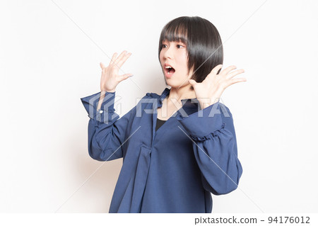 A young woman doing a surprised pose in front of a white background A young woman doing a surprised pose in front of a white background 94176012
