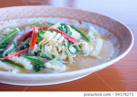 Stir fried squid with salted egg yolk mix with red capsicum, chop onion and chop spring onion in a patterned plastic dish on the wooden table. Complementary color. Stir fried squid with salted egg yolk mix with red capsicum, chop onion and chop spring onion in a patterned plastic dish on the wooden table. Complementary color. 94176271