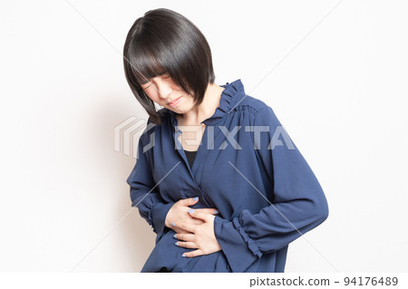 一位年輕女子在白色背景前把手放在肚子上 一位年輕女子在白色背景前把手放在肚子上 94176489