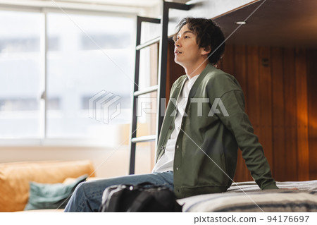 Man sitting on hotel bed 94176697