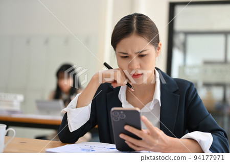Stressed young Asian businesswoman having a problem on her smartphone. Stressed young Asian businesswoman having a problem on her smartphone. 94177971