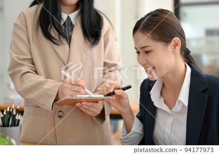 Pretty Asian businesswoman working and planning the project details with her coworker. Pretty Asian businesswoman working and planning the project details with her coworker. 94177973