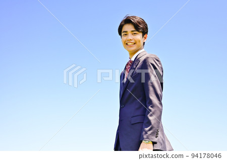 Young businessman with blue sky background Young businessman with blue sky background 94178046